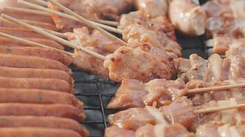 A grill with many different types of meat on skewers video