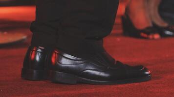 A close up of a man's shoes on a red carpet video