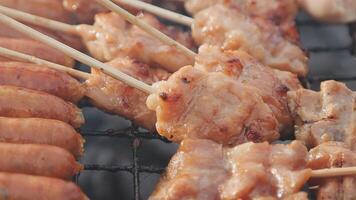 A grill with skewers of meat and sausage video