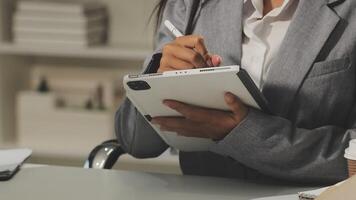 A woman in a business suit is writing on a tablet video