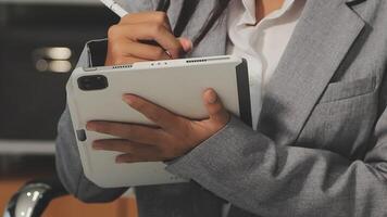 A woman in a suit holding a pen and tablet video
