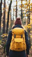 A woman with a yellow backpack walking through a forest photo