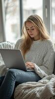 A woman sitting on a couch with a laptop photo