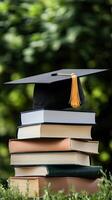 A graduation cap sits on top of a stack of books photo