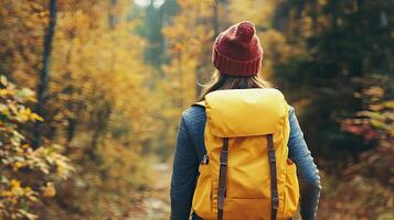 A woman with a yellow backpack walking through the woods photo
