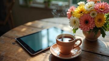 Flowers, tea, and tablet arranged on a wooden table photo