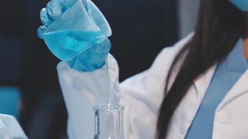 A woman in a lab coat is pouring liquid into a flask video