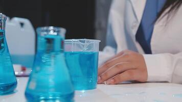 A person in a lab coat is working with blue liquid video