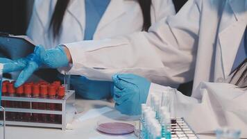 Two people in lab coats are working on a computer video