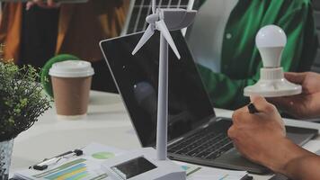 A person working on a laptop with a wind turbine video