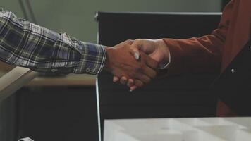 Two people shaking hands in front of a desk video