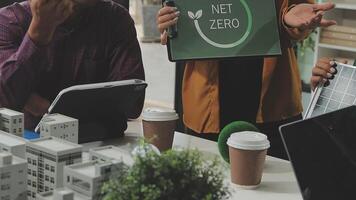 Three people sitting at a table with a net zero sign video