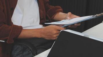 A man is sitting at a desk with a laptop and a clipboard video