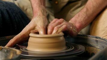 Hands unrecognizable artisan man master craftsman creating form shaping raw clay potter pottery spinning wheel process molding making ceramic pot workshop masterclass earthenware indoor craftsmanship video