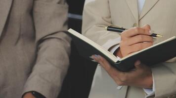 A man in a suit holding a pen and writing in a notebook video