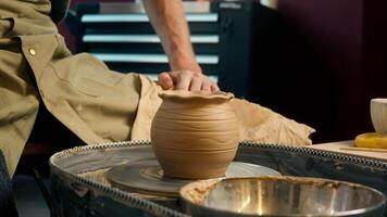 Potter man master sitting at studio craft craftsman pottery wheel spinning jug rotating ceramic cup clay workshop creating mug handmade hobby artist working handcraft male small business turning vase video