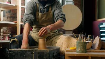Man potter working rotating spinning pottery wheel wet clay washing hands water workshop craft sculptor in apron creating pot studio craftsman ceramic bowl art artisan handicraft hobby male shaping video