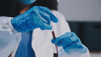 A person in a lab coat and gloves holding a tube video