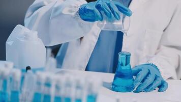 A person in a lab coat pouring liquid into a test tube video