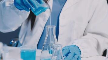 A woman in a lab coat is pouring liquid into a beaker video