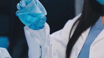 A woman in a lab coat is pouring liquid into a flask video