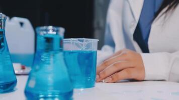 A person in a lab coat is working with blue liquid video