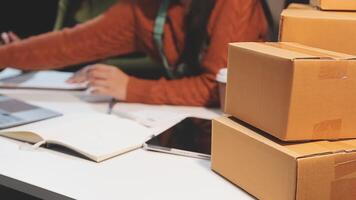 A woman is working on her laptop while sitting at a desk with a stack of boxes video