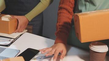 Two people are holding boxes and a laptop video