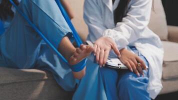 A woman in scrubs is sitting on a couch with her foot in a cast video