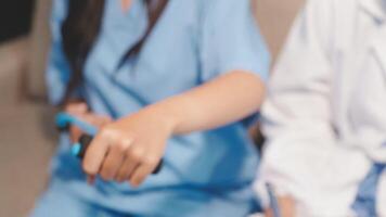 A nurse is holding a remote control while another person is sitting next to her video