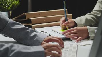 Two people working on a computer with a pen and paper video