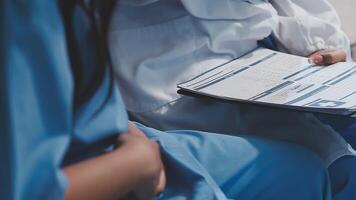 A doctor is holding a clipboard while sitting next to another person video