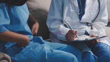 A doctor is writing on a clipboard while another person sits on a couch video