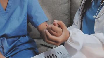 A nurse holding a patient's hand while another nurse is sitting on a couch video