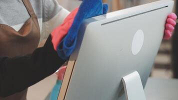A person wearing gloves and an apron is cleaning a computer video