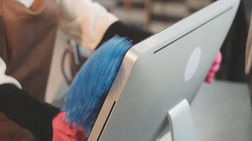 A person is cleaning a computer screen with a blue cloth video