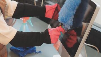 A person wearing gloves and a pink mitt is cleaning a computer video