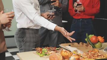 A group of people standing around a table with food and wine video