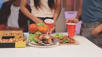 A group of people standing around a table with food video