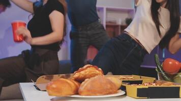 A group of people dancing in front of a table with pizza and drinks video