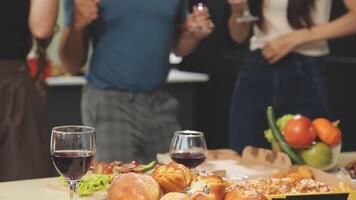 A group of people standing around a table with food and wine video