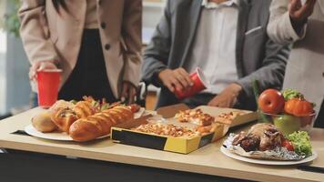 A group of people standing around a table with food video