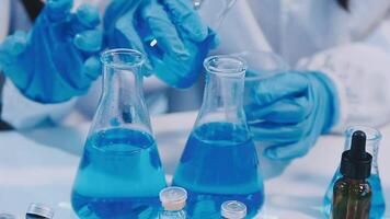 A person in a lab coat is holding a blue liquid video