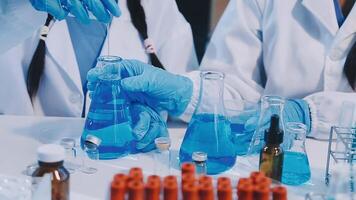 Two people in lab coats and gloves are working on blue liquid video