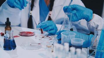 A person in a lab coat and gloves is working on a test tube video