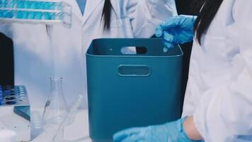 Two people in lab coats are holding a container video
