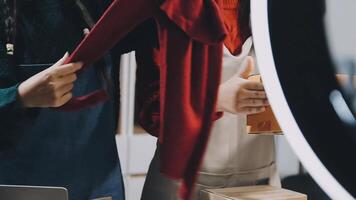 Two women are looking at a mirror while holding a red sweater video