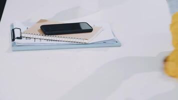 A person sitting on a desk with a phone and notebook video