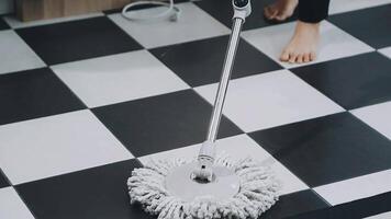 A person using a mop to clean a black and white checkered floor video