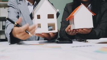 Two business people holding a house model video